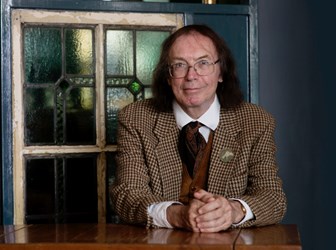 A portrait photograph of Ronald Hutton sat at a table