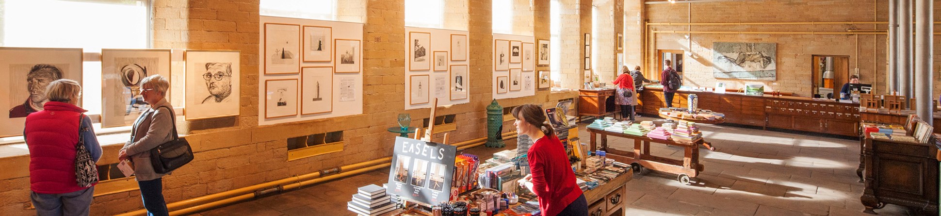 A young woman investigates goods on sale at a gift shop in a repurposed industrial building.