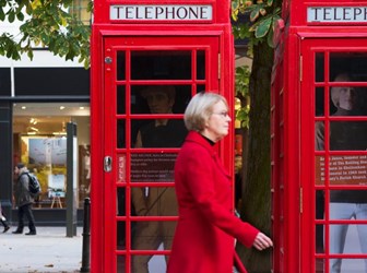 Woman walking past telephone kiosks in Cheltenham