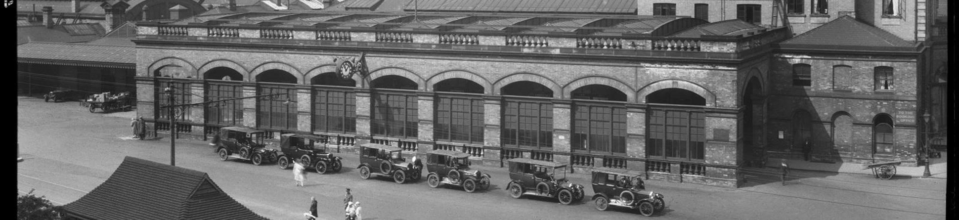 A view showing York Railway Station from an elevated position to the south-east, with a line of cars, probably taxis, parked along the road in front