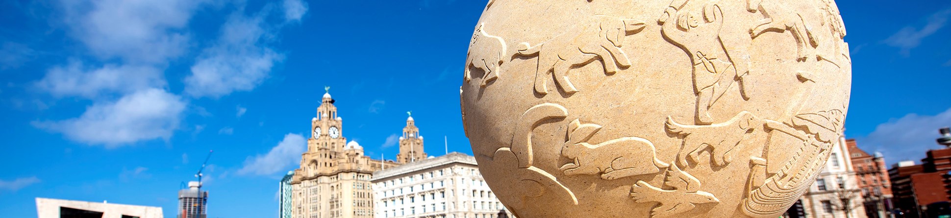 Stone ball engraved with images of people and animals on top of stone plinth