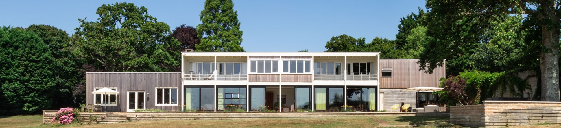 Flat-roofed timber clad house surrounded by trees