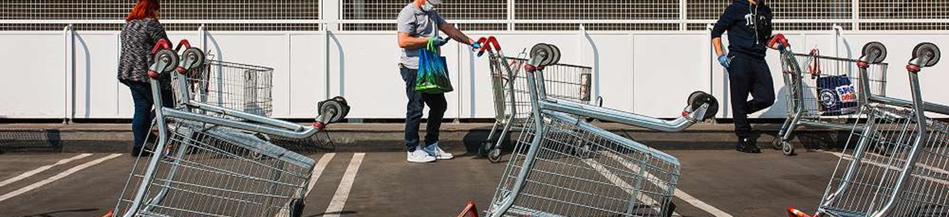 Three people standing 2 metres apart with supermarket trollies