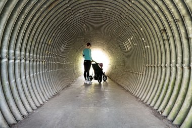 A woman in sportswear checks her mobile phone beside a pram.