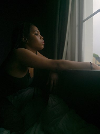 A photo of a woman staring out of her window.