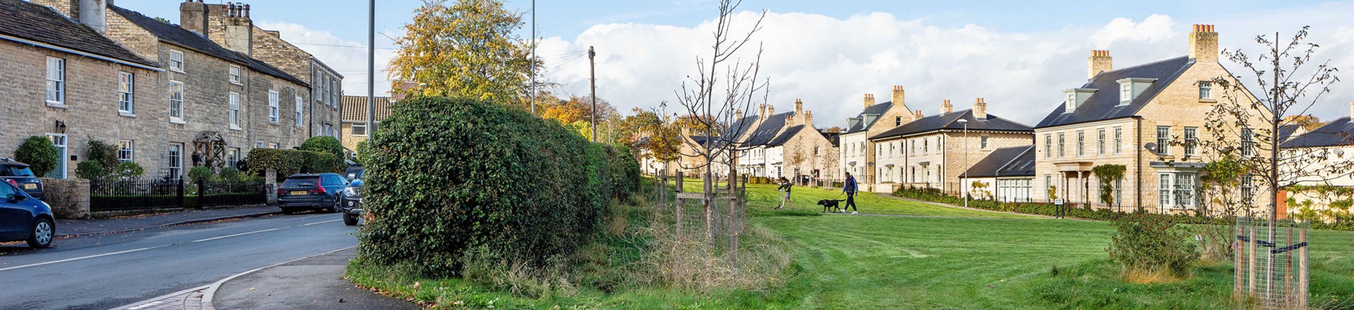 A view of a new housing development adjacent to a Village High Street with historic buildings.