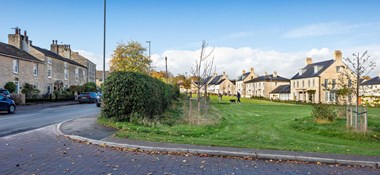 A view of a new housing development adjacent to a Village High Street with historic buildings.