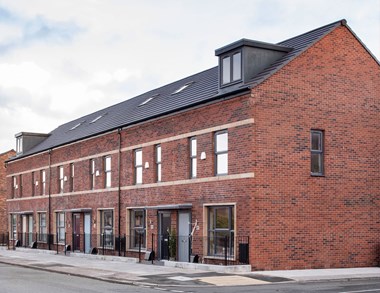 A terrace of brick modern housing, two storeys plus attic level.