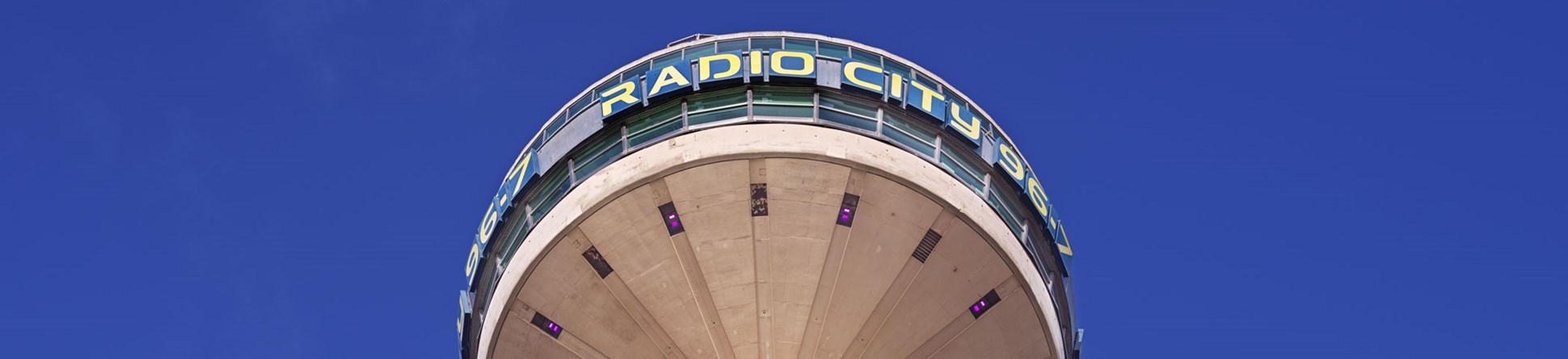 Photograph of the upper portion of a tall concrete radio tower with a circular viewing platform at the top.