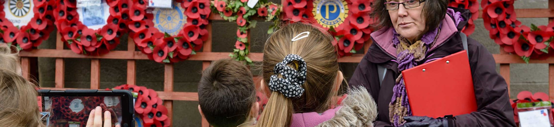 A group of children learning carring out a condition survey on a war memorial.