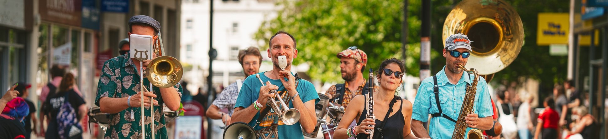 A troup of musicians walk along Weston-super-Mare high street paying wind instruments 