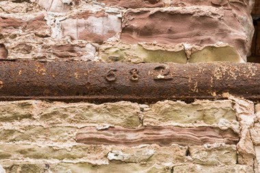 A photograph of a cast iron lintel with the date 1682 set into a stone wall.