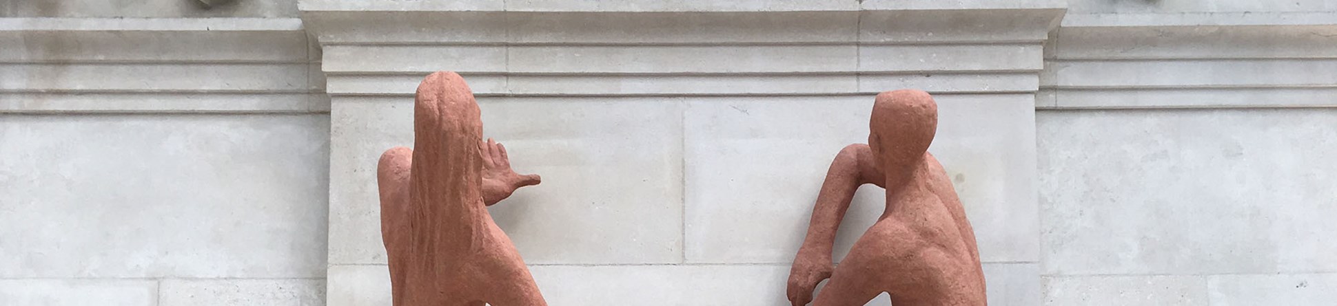 Terracotta sculpture of a male and female figure fixed to a marble clad wall in London Waterloo station.