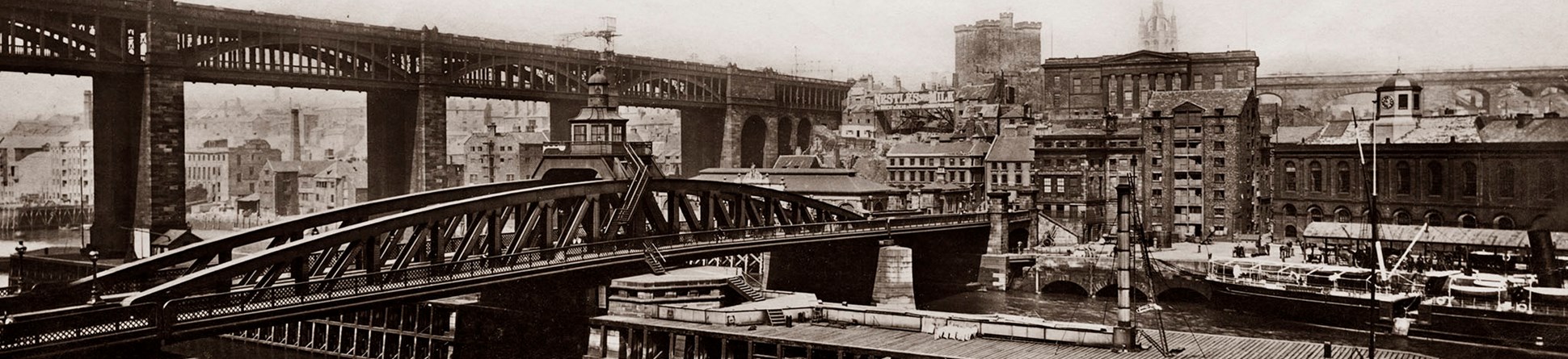 Archive sepia image showing a river with two bridges and a city beyond.