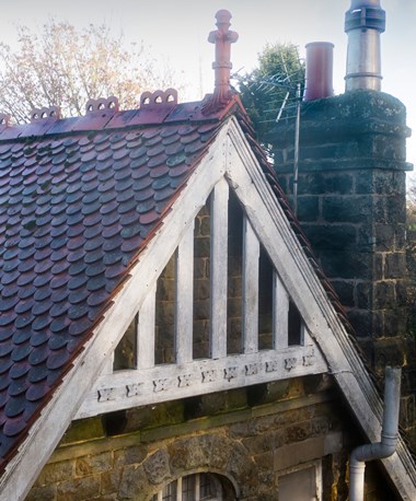 Tiled roof, gable and chimney of a stone house.