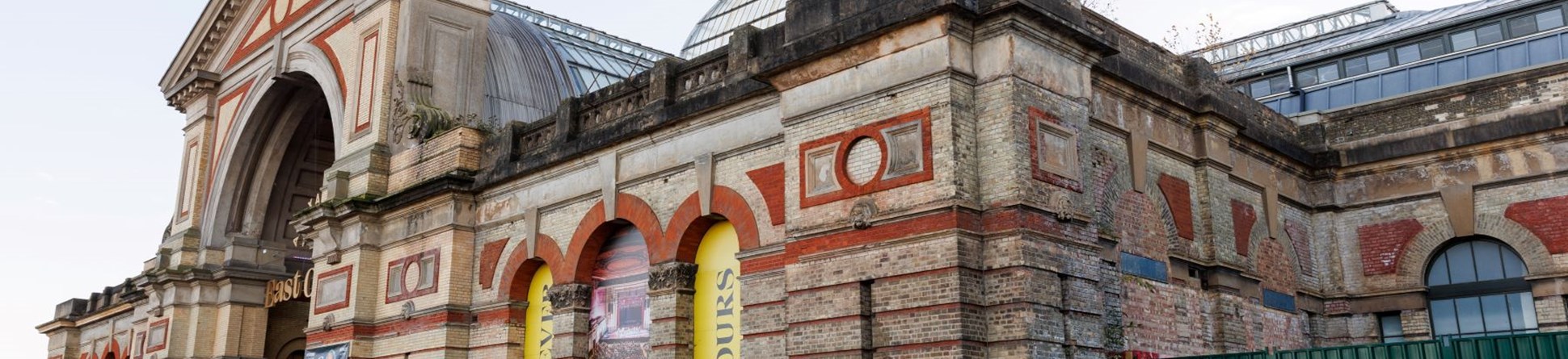 A photograph showing one elevation of a large building with decorative brickwork and arches.