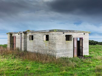 Exterior view of a concrete radar station beneath dark skies and surrounded by grass