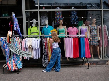 Young girl browsing a rack of clothing outside a shop.