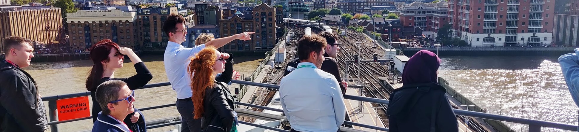 People looking across the Thames from a viewing point on top of a building.