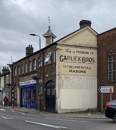 Ghost sign on the side of a 2-storey brick building.