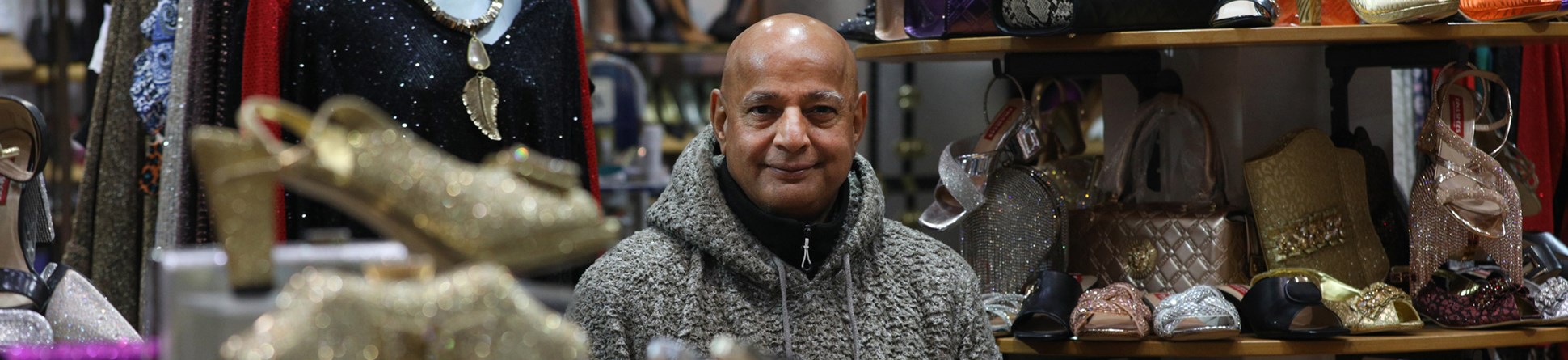 Portrait of a man in a women's fashion shop, surrounded by displays of shoes, clothing and accessories.