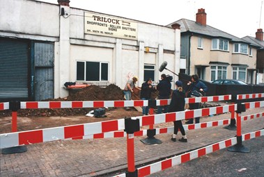 Film crew filming people excavating in front of a building