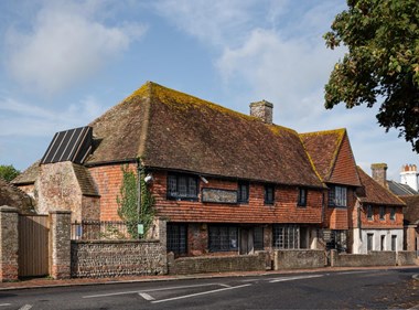 A slate-covered house with a sign saying "Antique Exports". A low wall separates it from the road in front.