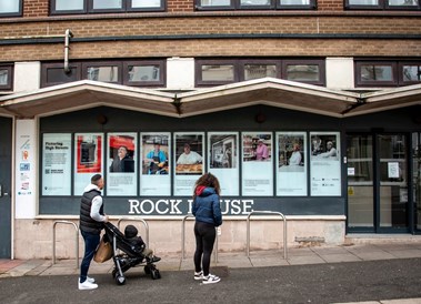 A woman and man, pushing a pram, looking at the installations in a window.