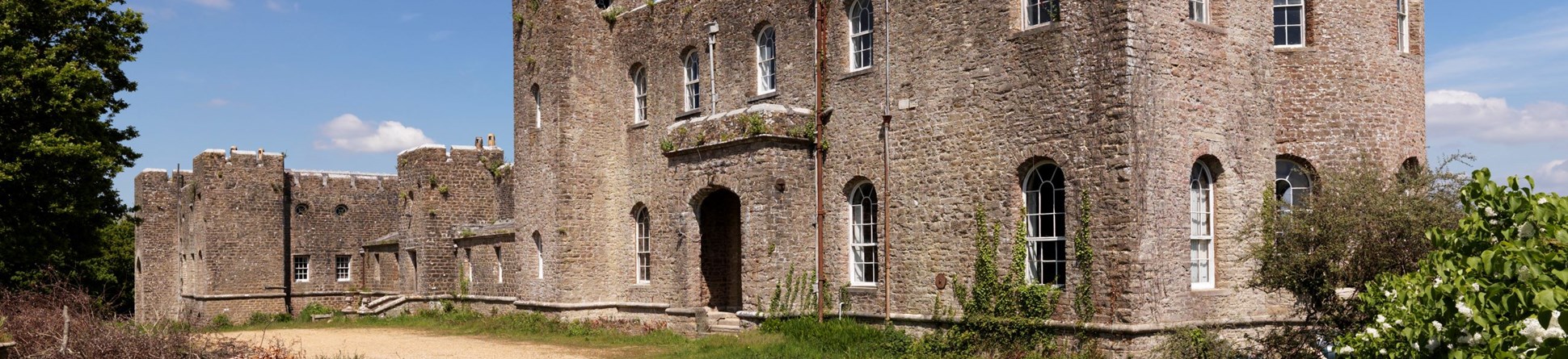 A large villa built of stone to resemble a castle in a coastal setting.