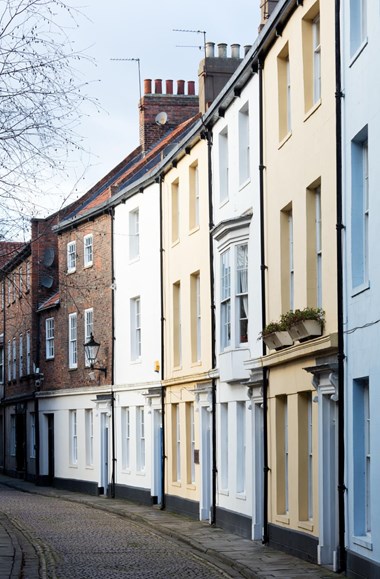 A row of terraced houses along a cobbled street.